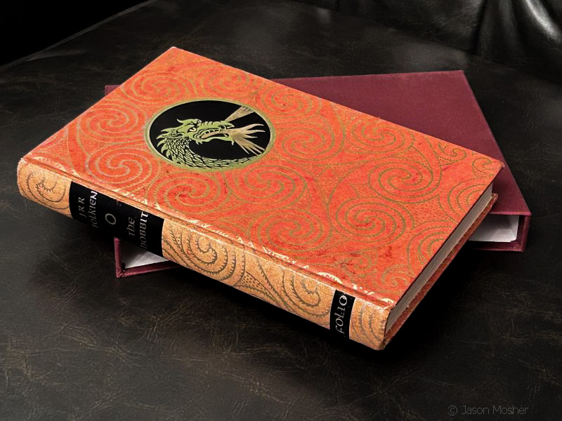 An orange color book laying on a leather chair.