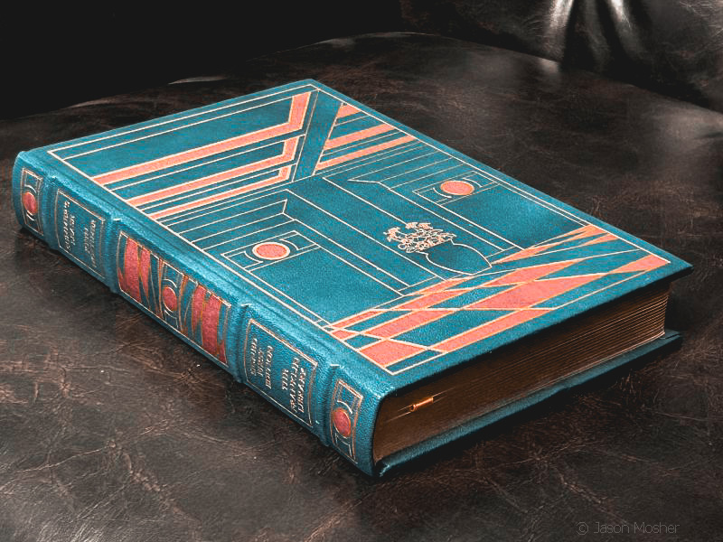 A blue colored leather classic book on a brown leather chair.